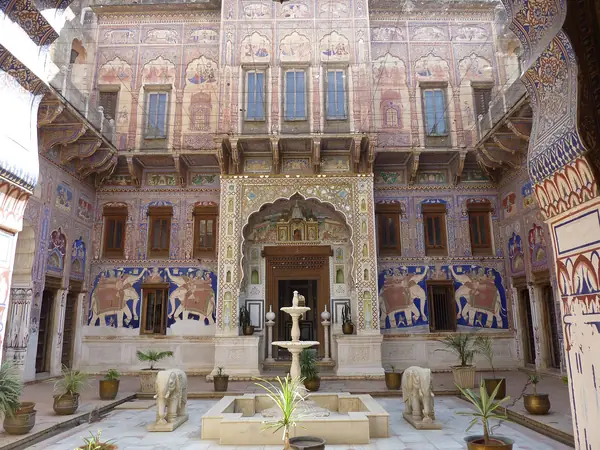 Painted haveli courtyard with arcaded verandahs and a stone fountain