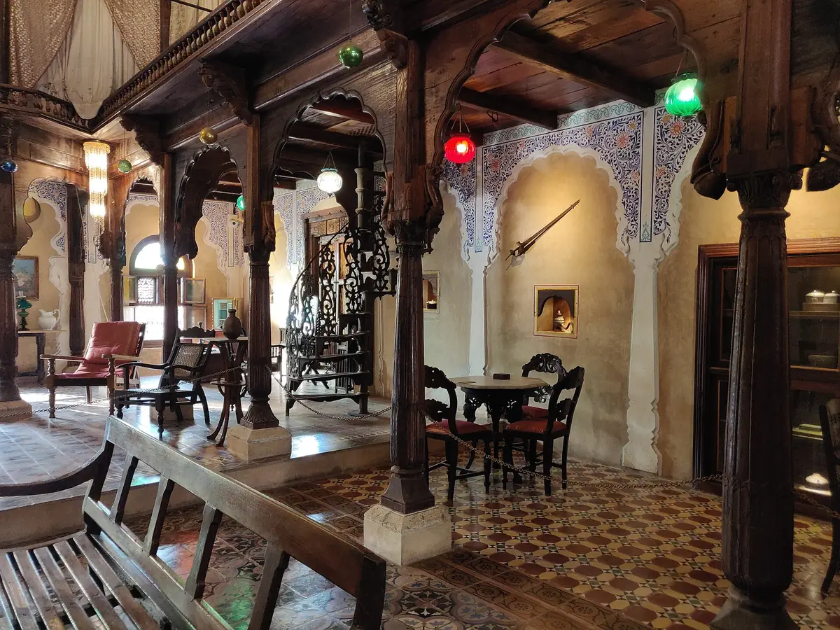 A heritage Deccan hall with carved timber columns, arched openings and traditional seating